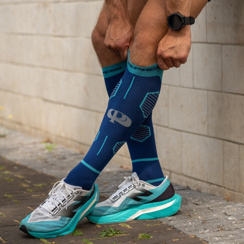 Person wearing blue compression socks and running shoes on a sidewalk.